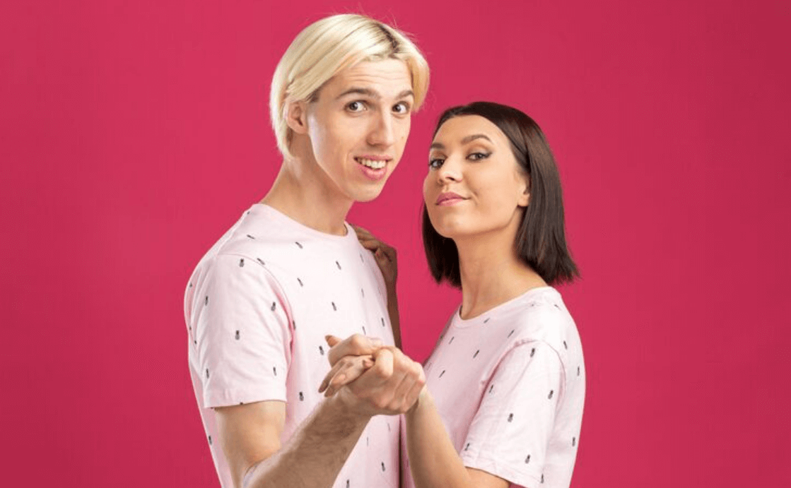 Two adults posing together against a pink background