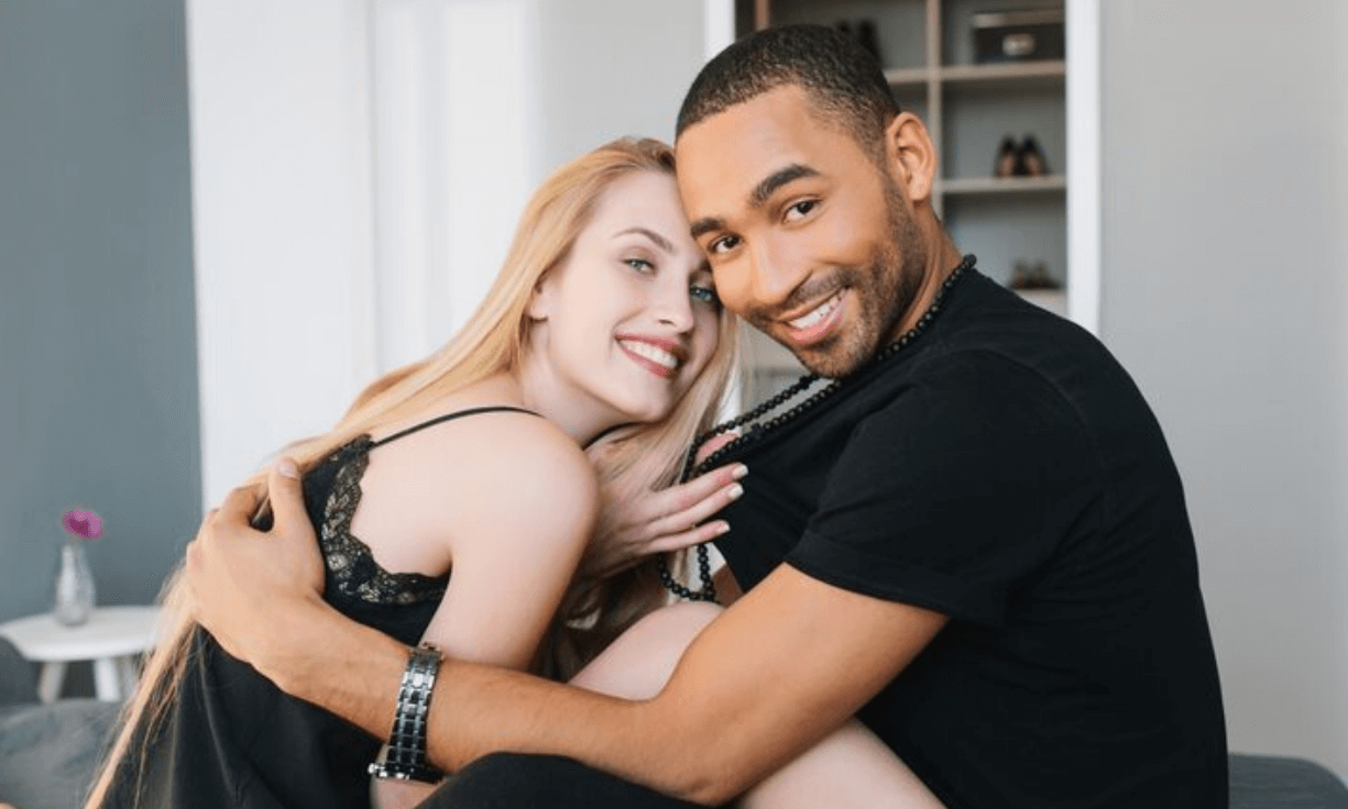 Two adults smiling together on a sofa
